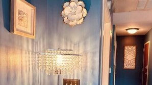 A hallway with a blue wall, a chandelier, a framed picture, and a patterned rug. - Your home away from home - Weekly (Charlotte)