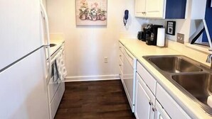 A kitchen with white cabinets, a stainless steel sink, a wooden floor, and a ceiling vent. - Your home away from home - Weekly (Charlotte)