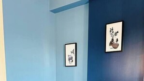 A corner room with a blue wall, a wooden table with a vase of sunflowers, and two framed pictures. - Your home away from home - Weekly (Charlotte)