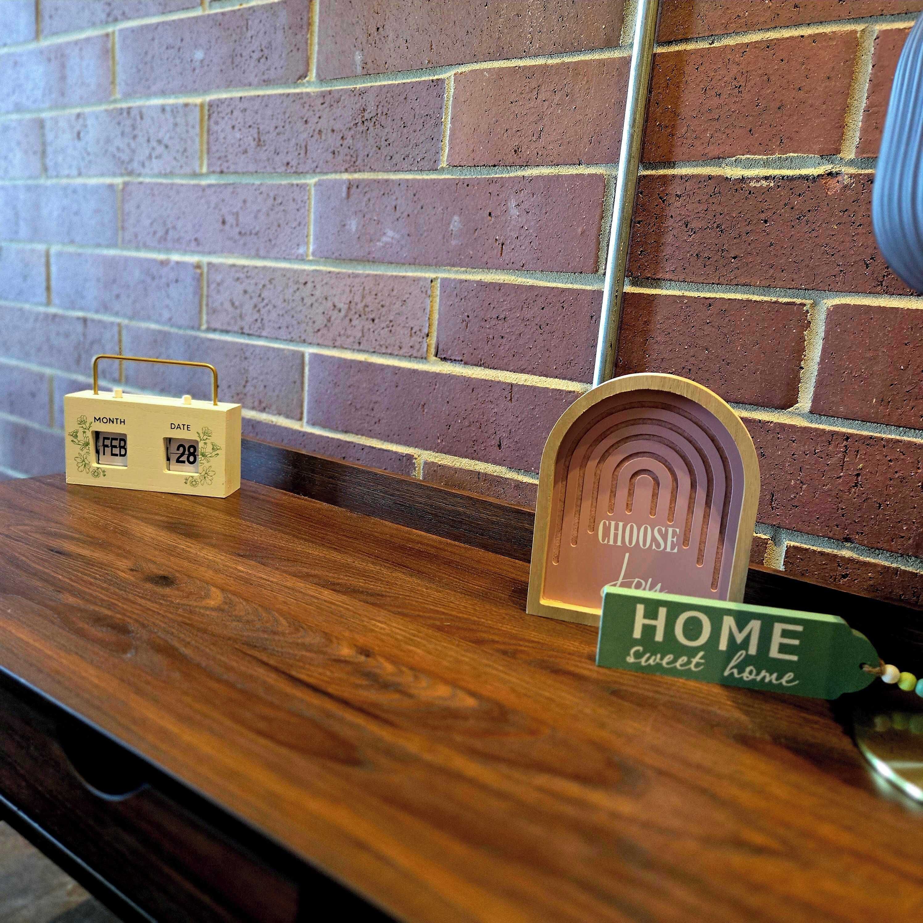 A wooden shelf with a calendar, a decorative sign, and a sign that says 'HOME sweet home'.