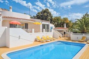A pool area with a clear blue pool, yellow sun loungers, and white walls. - Villa Emerald Sun (Lagoa)