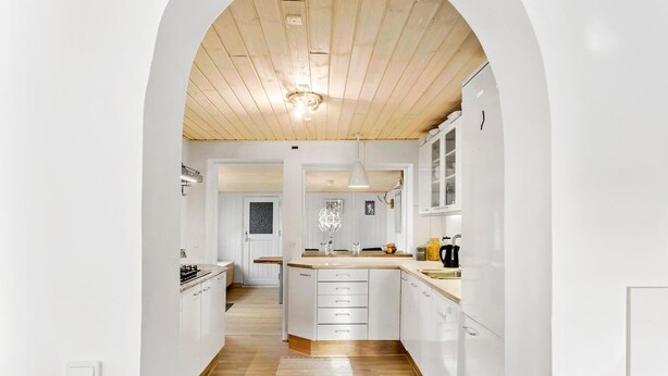 A modern kitchen with white cabinetry, a wooden ceiling, and a central island. - Nice home in Nexø with WiFi (Nexø)