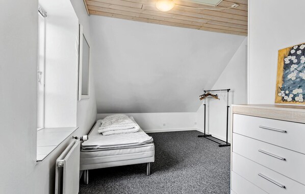 A small, compact bedroom with a single bed, a radiator, a wooden ceiling, and a small dresser. - Gorgeous home in Nexø with WiFi (Nexø)