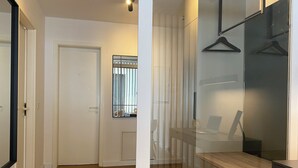 A hallway with a wooden floor, a white door, and a glass partition with a bench and a table.