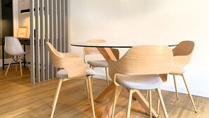 A modern dining area with a round table, wooden chairs, and a pendant light.