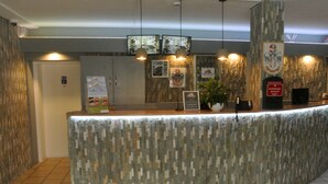 A reception area with a textured counter, framed pictures on the wall, and a potted plant. - smal-Apartment (Ostfildern)