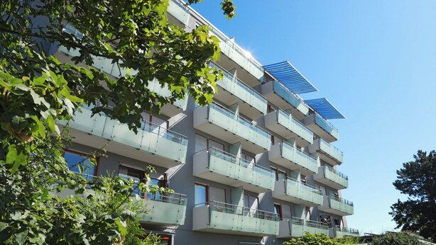 A multi-story residential building with balconies, a solar panel, and surrounding greenery. - smal-Apartment (Ostfildern)