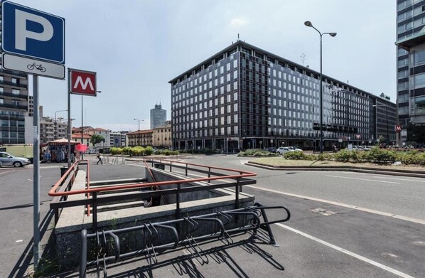 A modern building with a parking sign and a bike rack in the foreground.