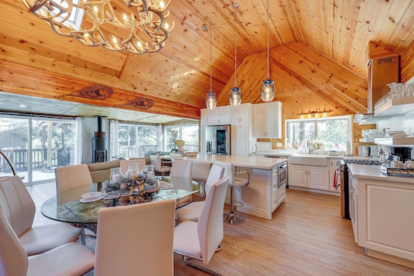 Una cocina amplia con techos de madera, un comedor con mesa de vidrio y vistas al exterior.