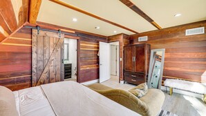 A bedroom with a bed, wooden walls, a wardrobe, and a mirror. - Wraparound Deck & Grill: Wrightwood Cabin Near PCT (Wrightwood)