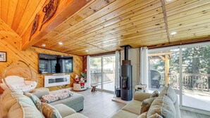 A cozy living room with a large sofa, a fireplace, and a television. - Wraparound Deck & Grill: Wrightwood Cabin Near PCT (Wrightwood)