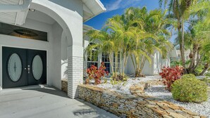 A modern house with a stone pathway leading to a double door, surrounded by palm trees and a well-maintained garden. - 10 Mi to Beach: Pet-friendly Home in Punta Gorda! (Punta Gorda)