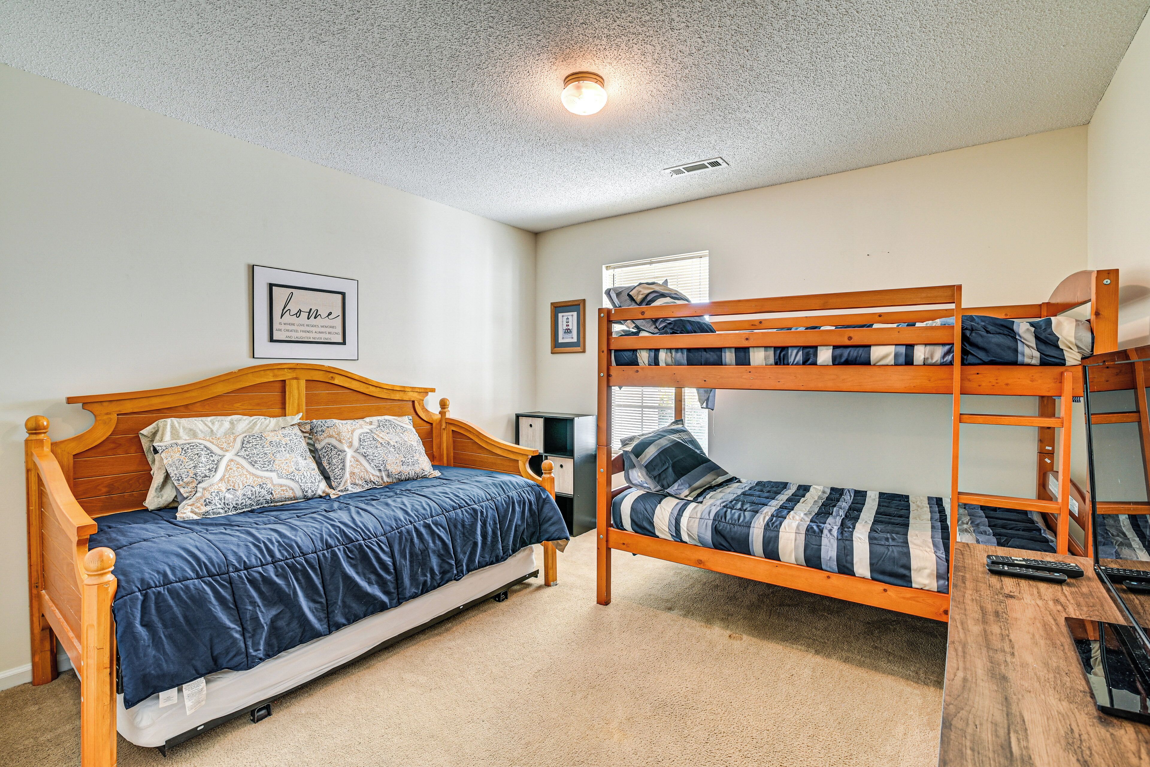 A bedroom with a single bed, a bunk bed, and a desk with a laptop.
