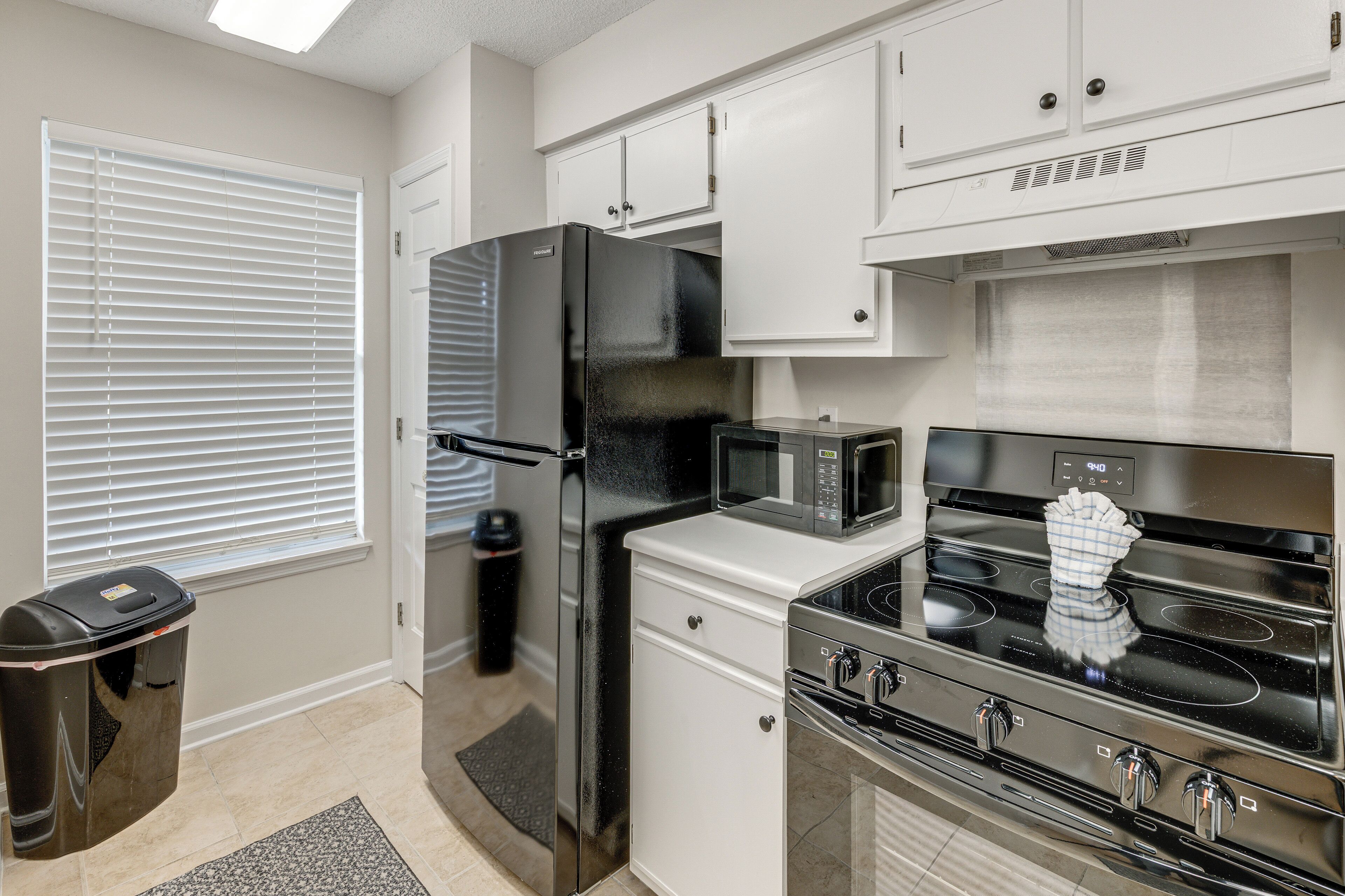 A kitchen with a refrigerator, microwave, stove, and cabinets.