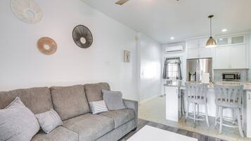 A modern living room with a grey sofa, a white coffee table, and a ceiling fan.