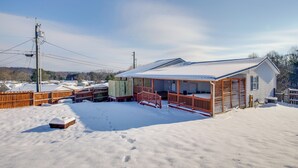 Ein Haus mit überdachter Veranda, umzäunter Garten und schneebedecktem Dach.