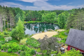A lakeside property with a dock, a red building, and lush greenery. - Hot Tub & Private Sauna: Wausau Family Home (Wausau)