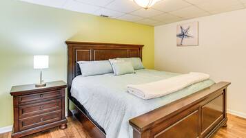 A bedroom with a wooden bed, a nightstand, and a wall-mounted lamp.