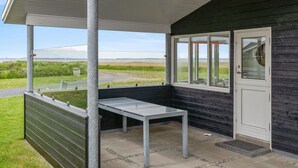 A covered outdoor area with a table and chairs, a door, and a view of the beach. - 2 bedroom stunning home in Vinderup (Vinderup)