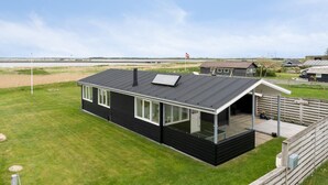 A modern black house with a large glass window, a solar panel, and a wooden deck. - 2 bedroom stunning home in Vinderup (Vinderup)