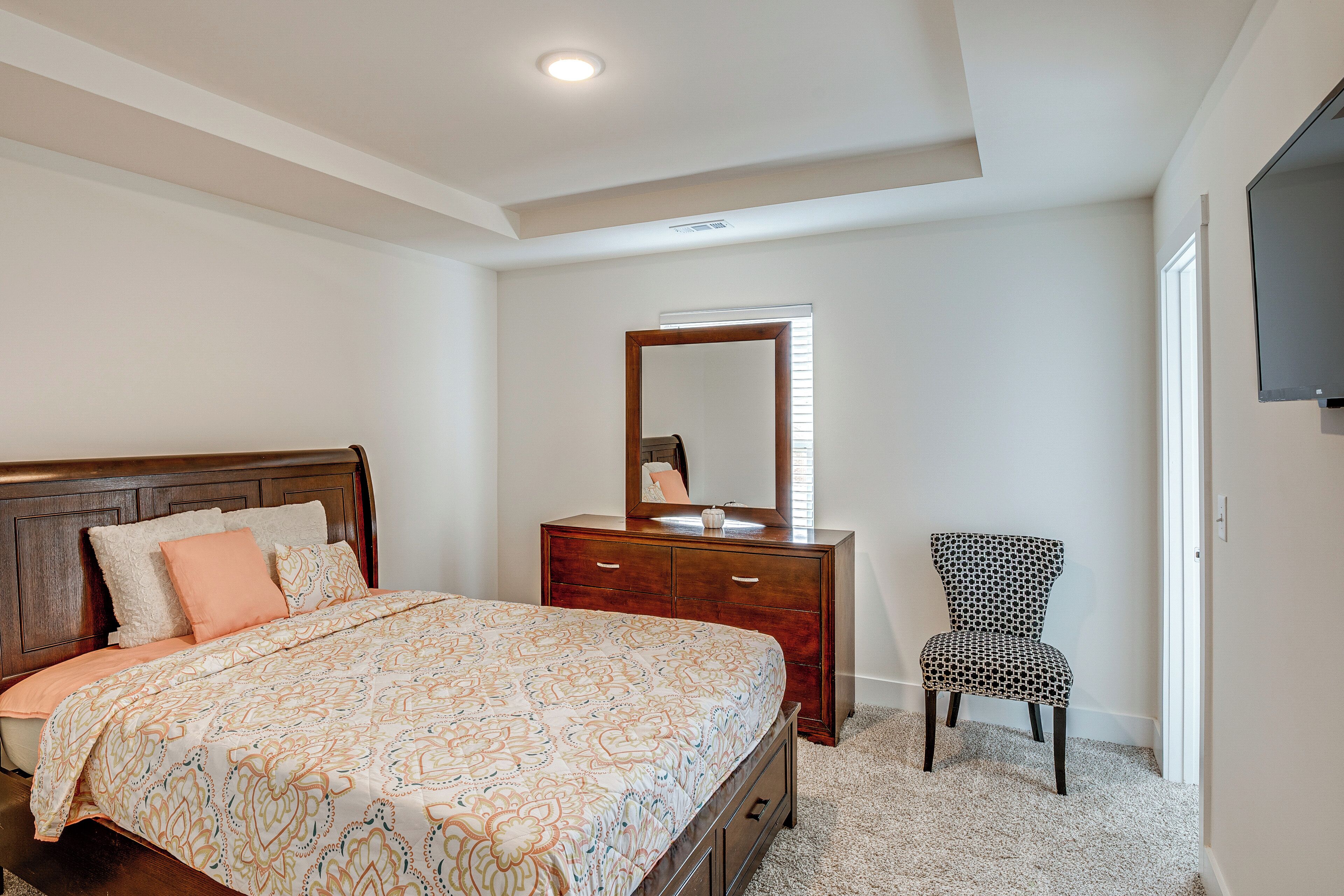 Ein Schlafzimmer mit Bett, Schminktisch, Stuhl und Spiegel.