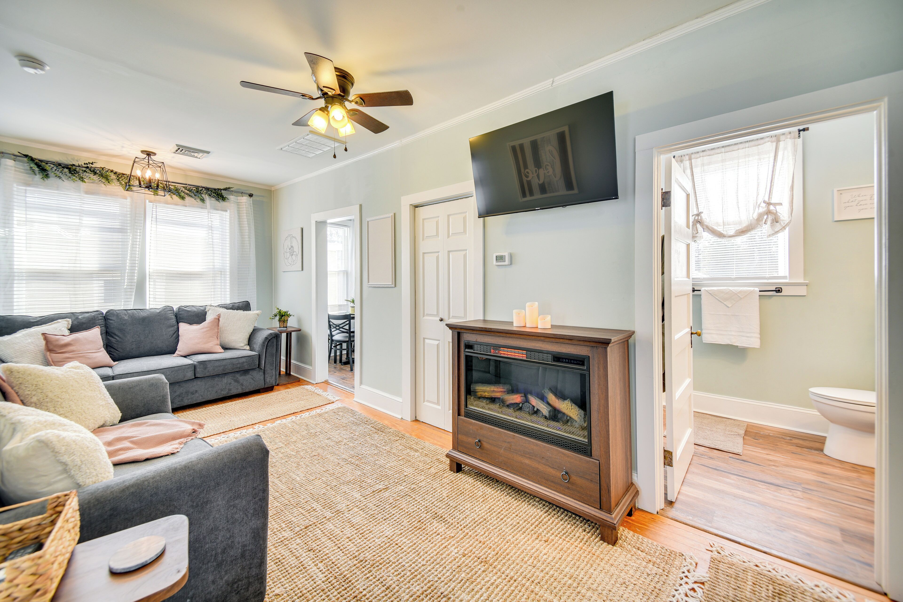 A living room with a grey sofa, a wooden entertainment center, and a ceiling fan.