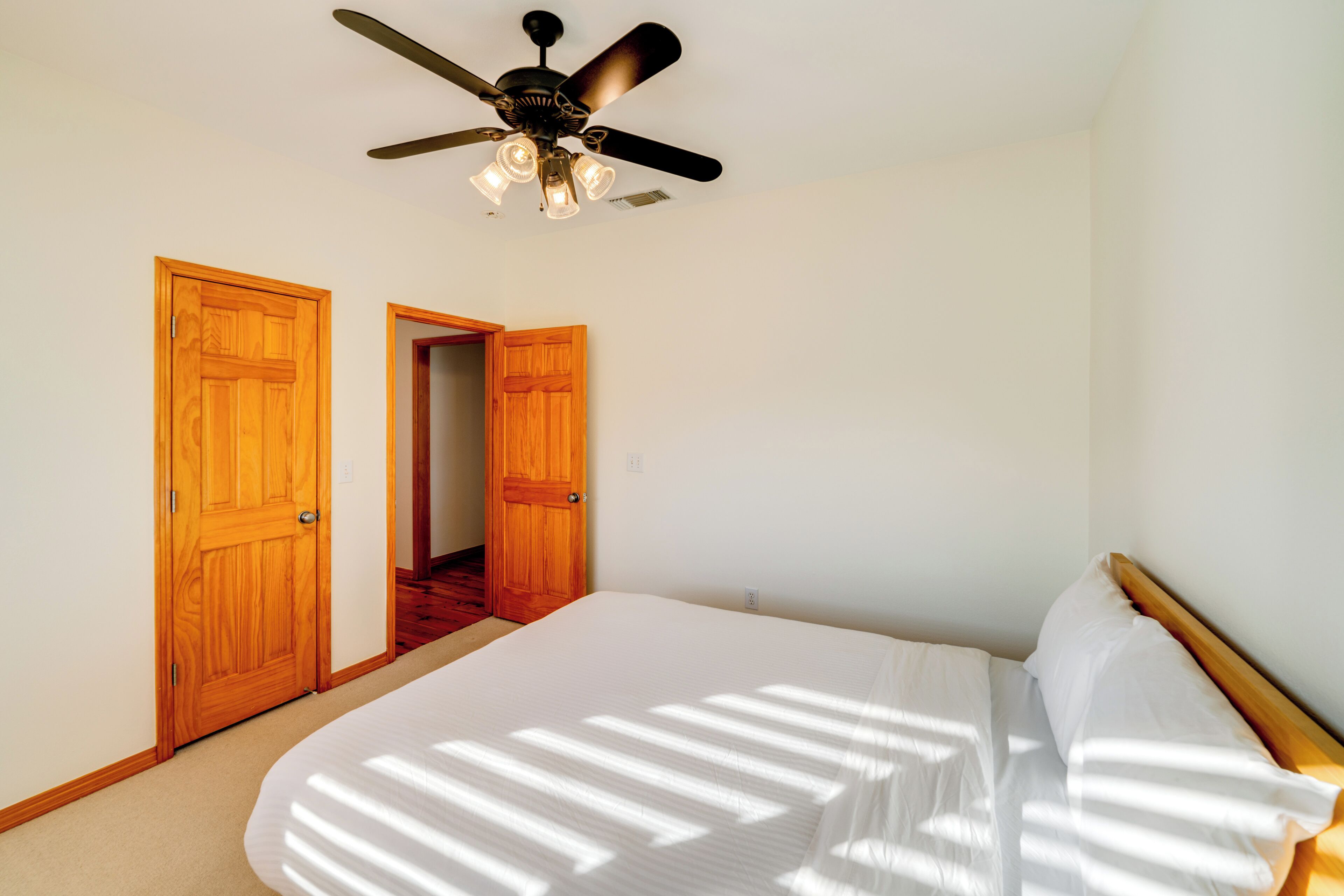 Una camera da letto con un letto, porte in legno e una ventola a soffitto.
