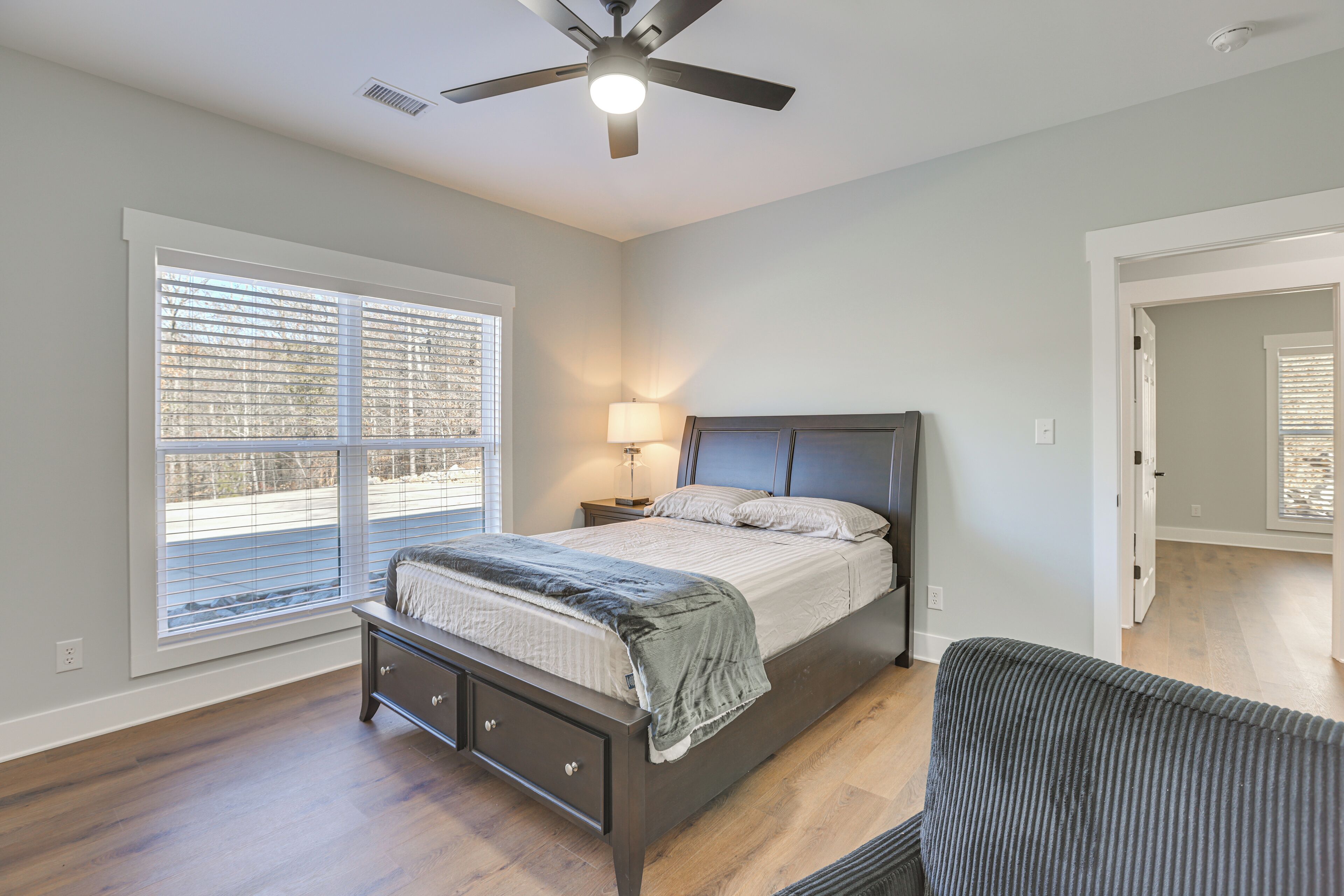 A bedroom with a bed, bedside table, lamp, and a ceiling fan.