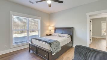 A bedroom with a bed, bedside table, lamp, and a ceiling fan.