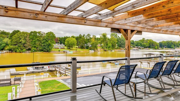 A wooden deck with rocking chairs overlooking a river and dock area. - Community Perks + Views: Cozy Lake Norman Cottage (Sherrills Ford)