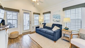 A well-lit living room with a blue sofa, a wooden side table, and a ceiling fan. - Community Perks + Views: Cozy Lake Norman Cottage (Sherrills Ford)