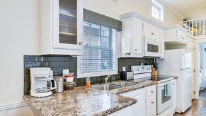 A kitchen with white cabinets, a granite countertop, a coffee maker, a microwave, and a refrigerator. - Community Perks + Views: Cozy Lake Norman Cottage (Sherrills Ford)