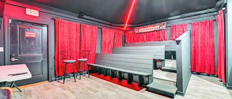 A theater with red curtains, an exit sign, and a bench seating area.
