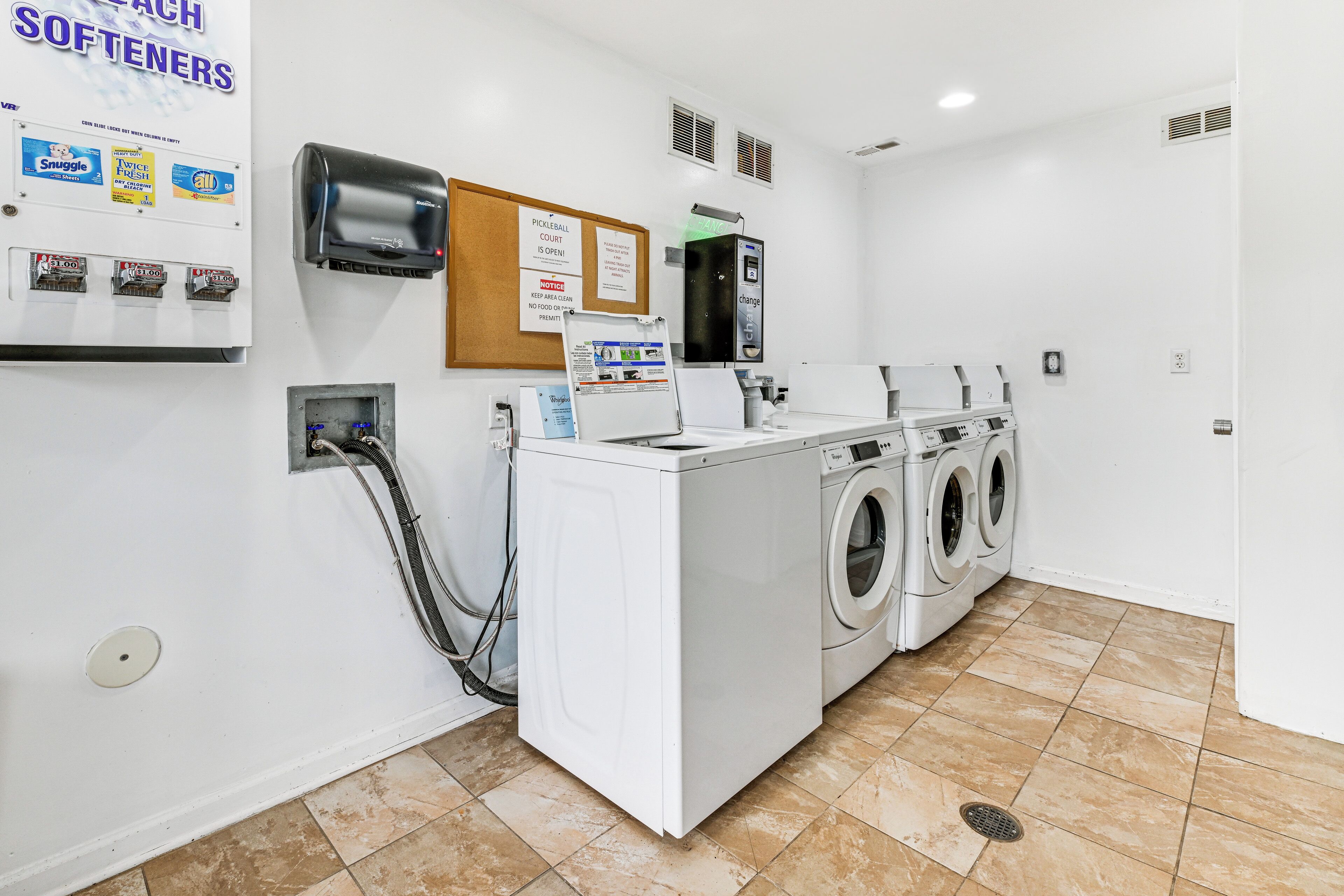 A laundry room with a washing machine, dryer, and a paper dispenser.
