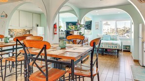 Un comedor amplio con techos altos y arcos, una cocina con electrodomésticos modernos y vistas a la ciudad a través de grandes ventanales.