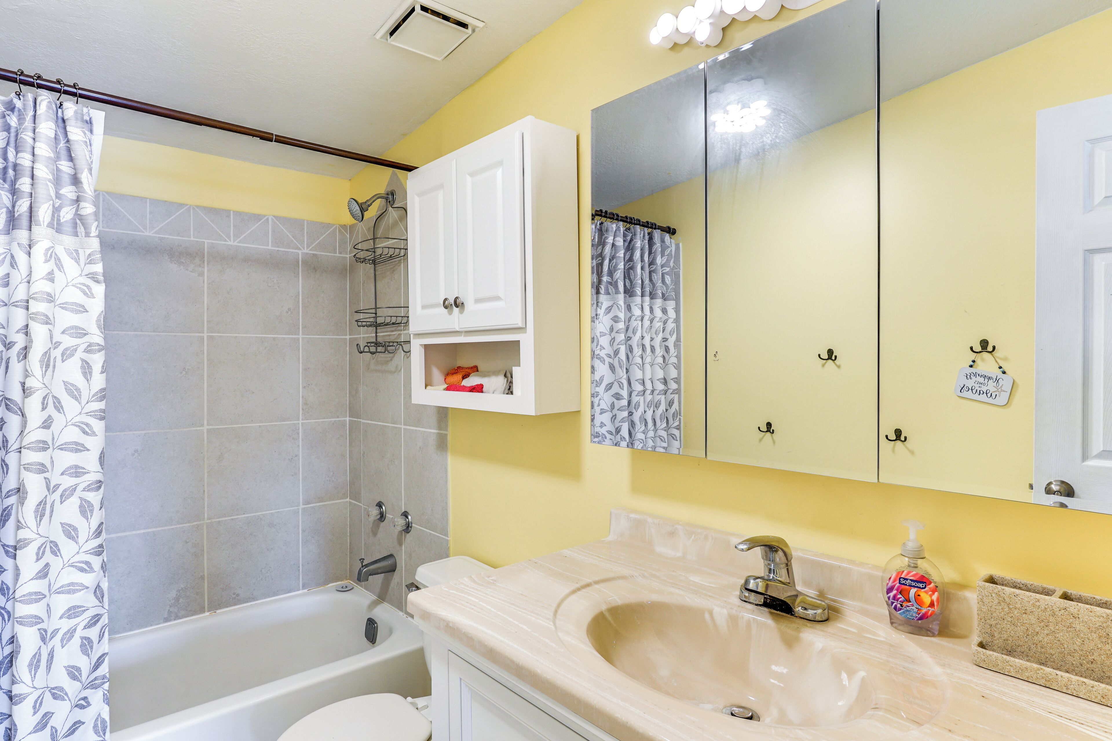 A bathroom with a bathtub, a sink, a mirror, and a shower curtain.
