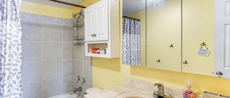 A bathroom with a bathtub, a sink, a mirror, and a shower curtain.