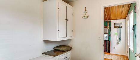 A bedroom with a bed, a white wardrobe, a pillow on the nightstand, and a door leading to another room.