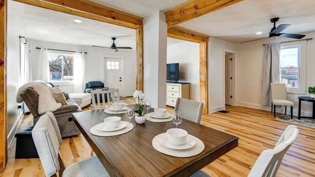 Un vaste espace de vie comprenant une table à manger en bois pour quatre personnes, un canapé et un téléviseur en arrière-plan.