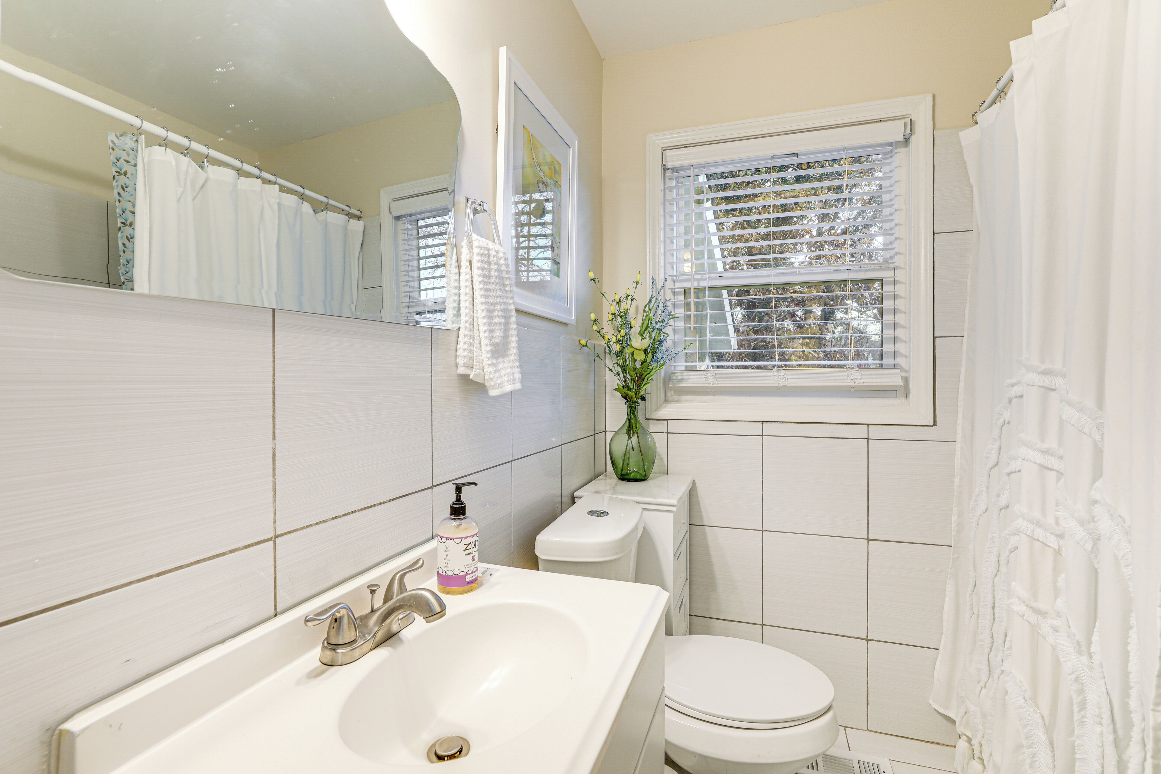 A bathroom with a white sink, toilet, and shower curtain.