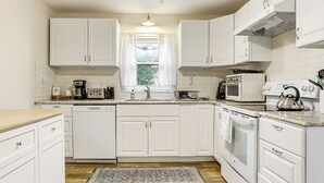 A kitchen with white cabinets, a dishwasher, a microwave, an oven, and a kettle. - 1 Mi to Stone Mountain Park: Outdoor Haven! (Stone Mountain)