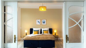 Een slaapkamer met een bed, twee bedlampjes en een kunstwerk aan de muur.