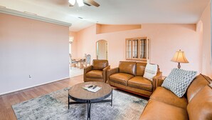 A living room with a brown leather sofa, a round coffee table, and a ceiling fan. - Hike, Boat, Golf & Unwind: Lake Havasu City Home! (Lake Havasu City)