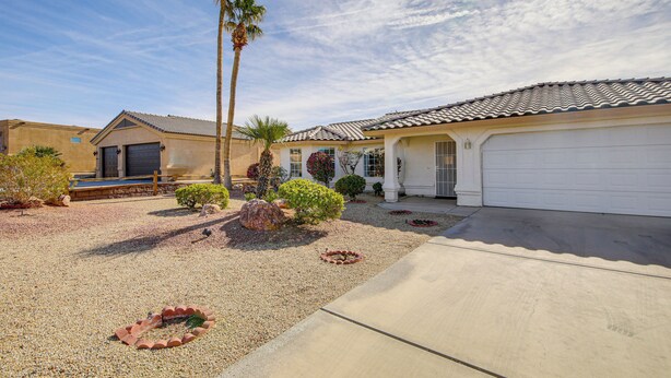 A residential property with a garage, a driveway, and a landscaped garden with palm trees and shrubs. - Hike, Boat, Golf & Unwind: Lake Havasu City Home! (Lake Havasu City)