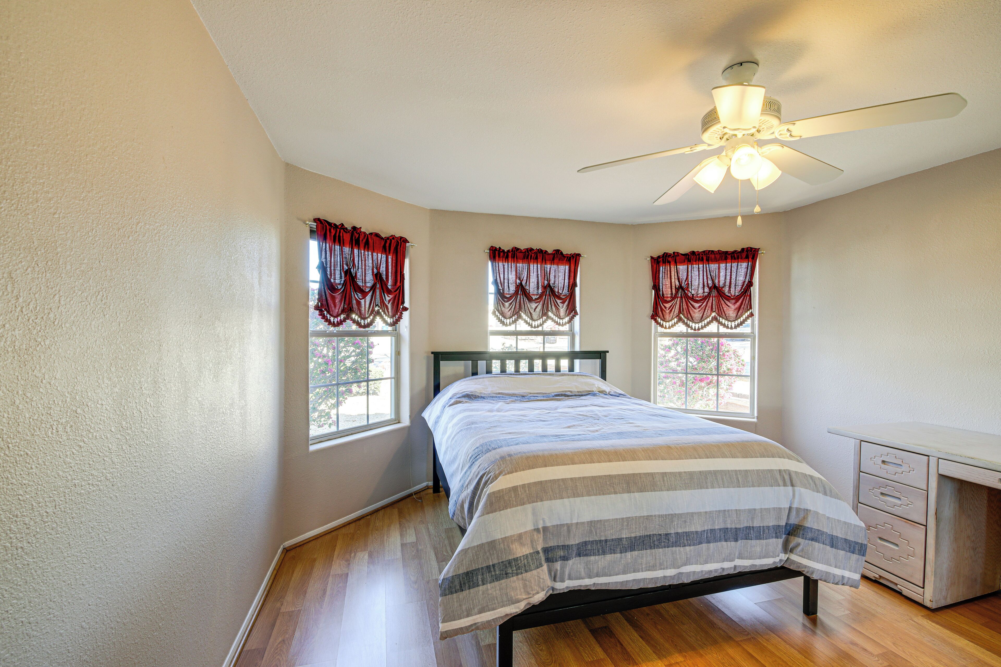 A bedroom with a bed, a desk, and a ceiling fan.