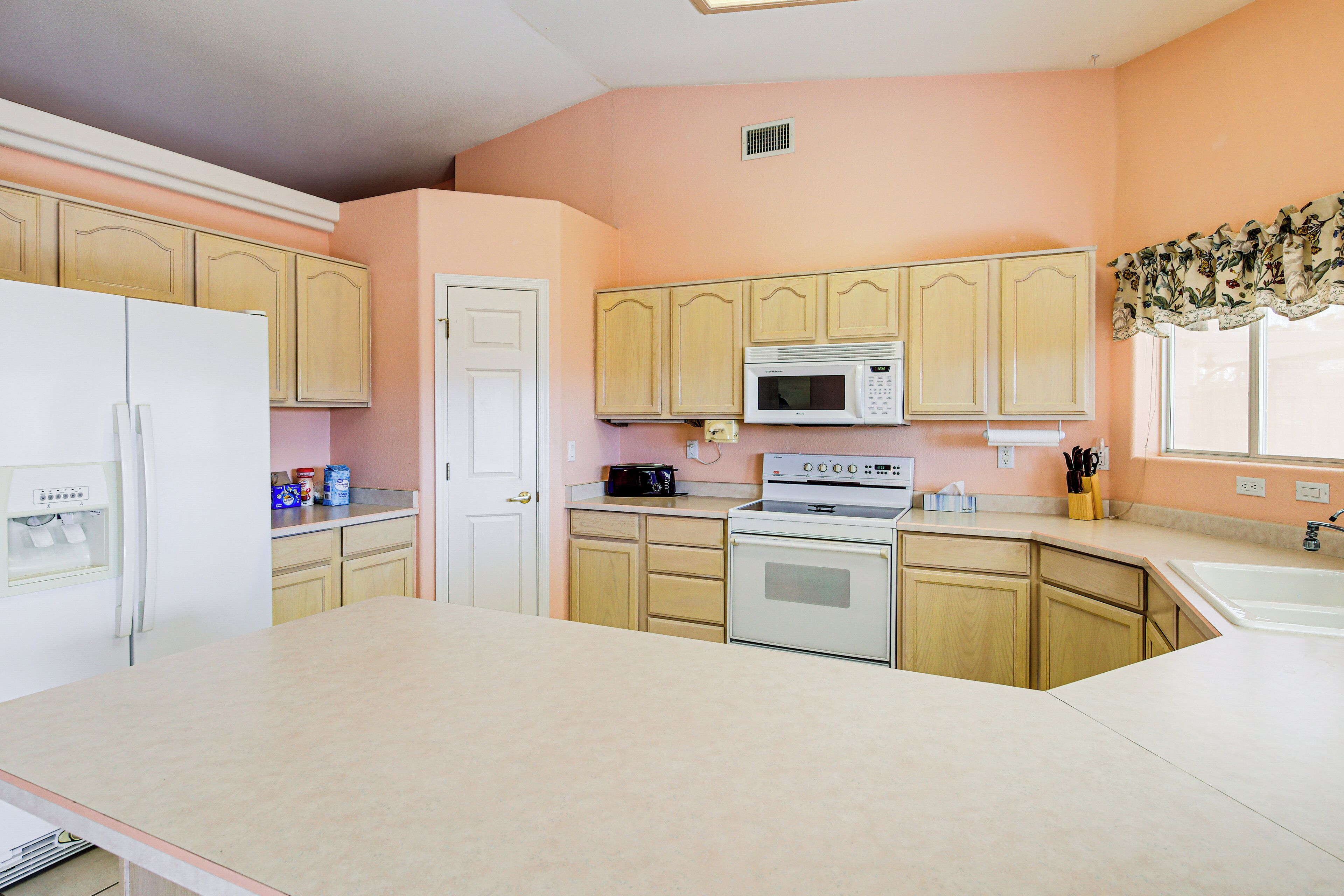 A kitchen with wooden cabinets, a white refrigerator, a microwave, and an oven.