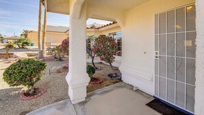 A covered outdoor area with a palm tree, a flowering bush, and a metal gate. - Hike, Boat, Golf & Unwind: Lake Havasu City Home! (Lake Havasu City)