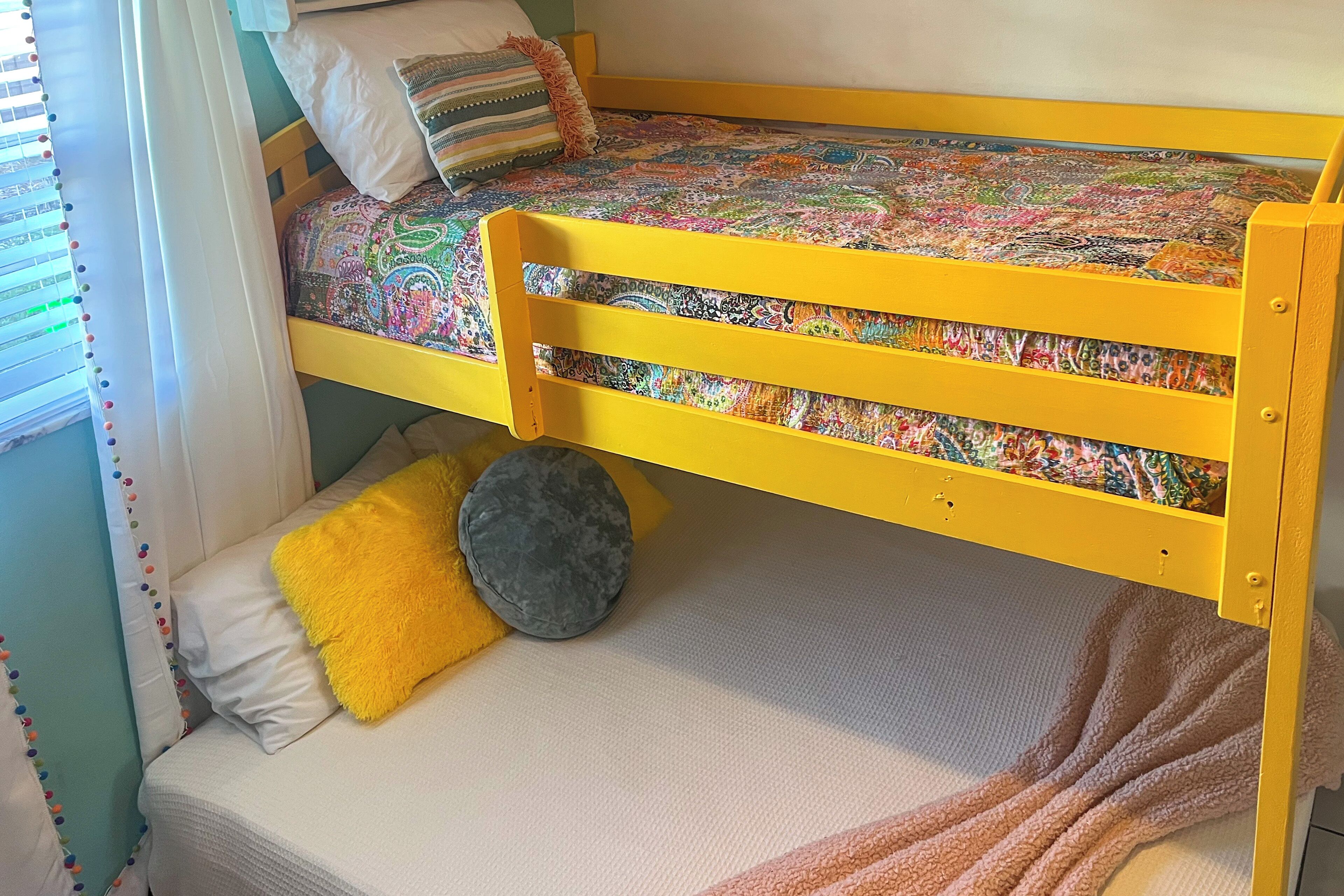 Ein Stockbett mit einer bunten Decke, Kissen und einer Wolldecke.