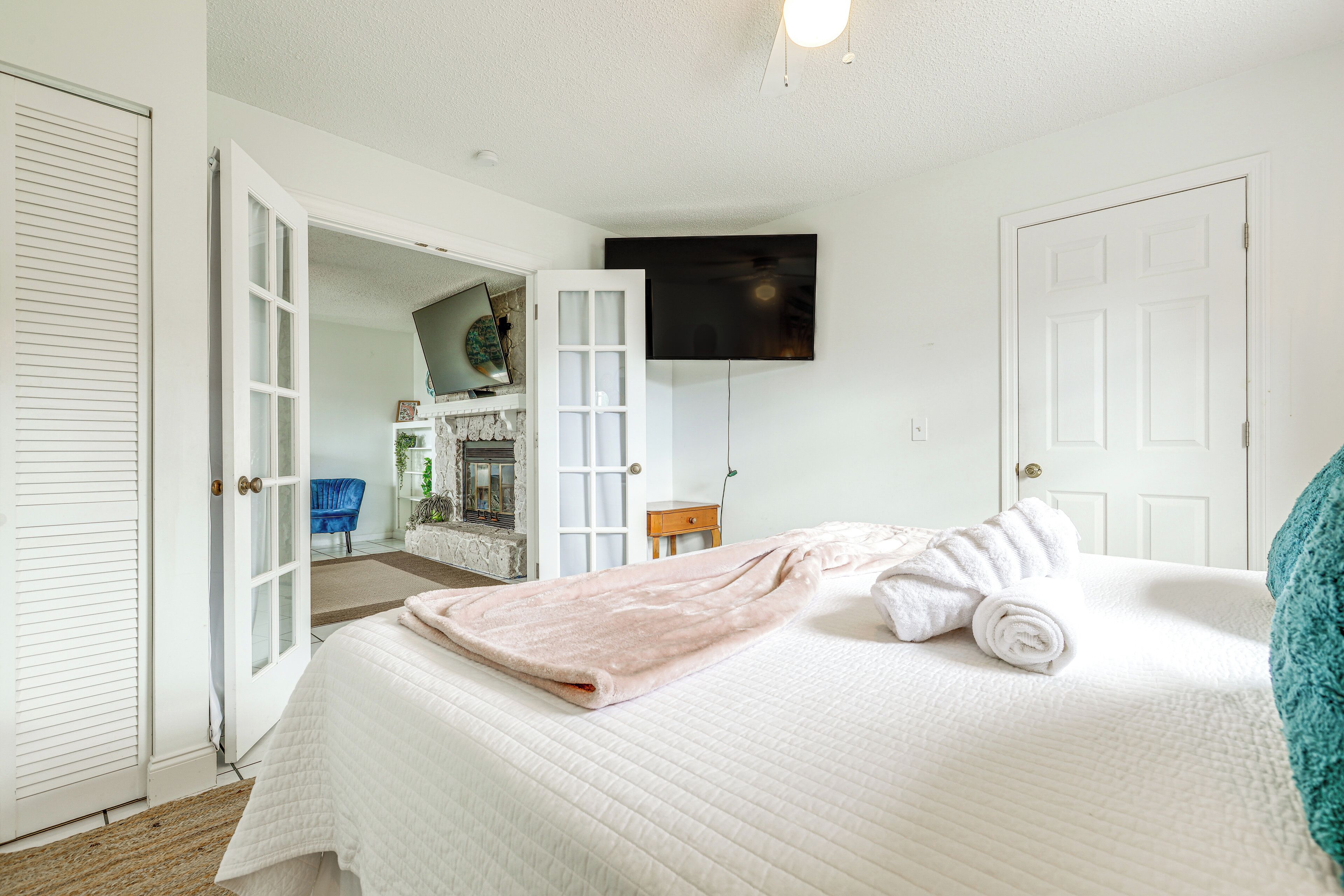 A bedroom with a bed, a TV mounted on the wall, and a bathroom visible through an open door.