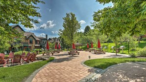 Ein Innenhof mit Picknicktischen und roten Sonnenschirmen, umgeben von üppigem Grün und einem Ziegelweg.